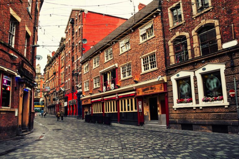 A street filled with charming old vintage buildings in Liverpool fronted by red brick and strung with electric wires.