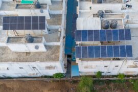 The roofs of two commercial buildings sharing a lot. There are solar panels installed on both of the buildings.