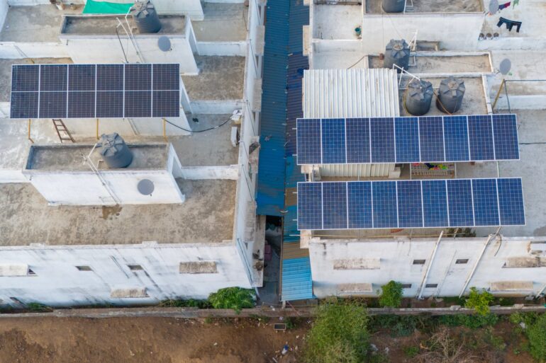 The roofs of two commercial buildings sharing a lot. There are solar panels installed on both of the buildings.