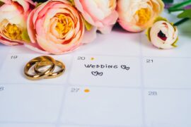 A close-up view shows an open calendar with "wedding day" written on a date. Two gold rings sit next to that date.
