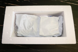 An open white Styrofoam container with no lid. Inside the container is a white, crumpled up ice pack.