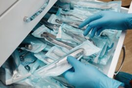 A surgical room with a pull out drawer full of disposable surgical instruments. There's a gloved professional grabbing one.