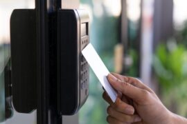 A close-up view shows a person holding a blank key card up to a black card reader with clear buttons.