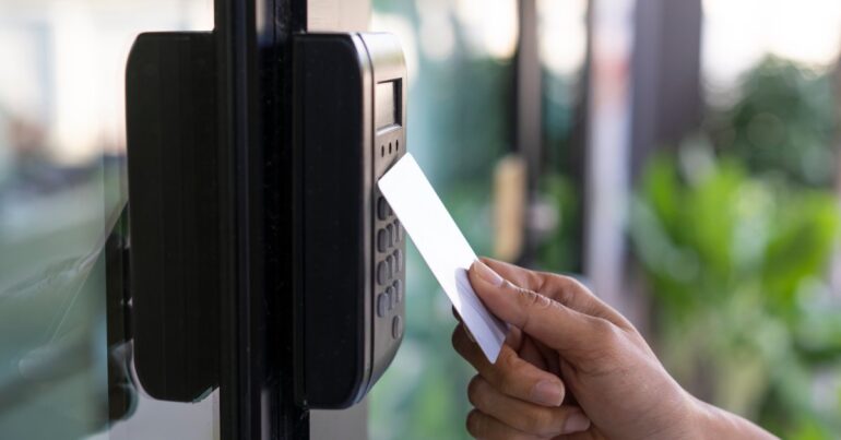 A close-up view shows a person holding a blank key card up to a black card reader with clear buttons.