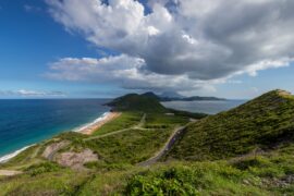 An overview of a mountainous Caribbean island with a winding road in the middle of the green mountains.