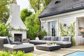 A cozy backyard sitting area. There is an outdoor fireplace, two sectionals, and an ottoman.