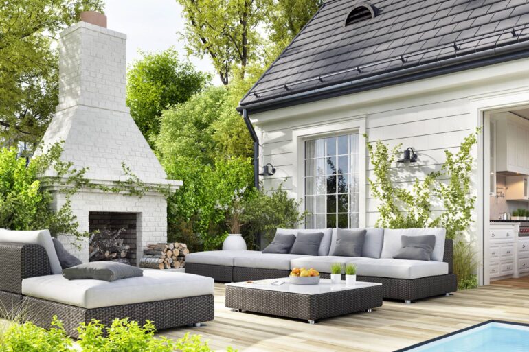 A cozy backyard sitting area. There is an outdoor fireplace, two sectionals, and an ottoman.