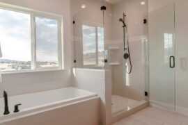 A white, clean, sleek showroom bathroom with a built-in bathtub and frameless shower stall, accented with black hardware.