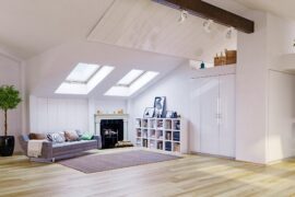 A living room with a slanted ceiling that has two skylights. There’s a couch in the corner that has throw pillows on it.