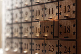 A close-up of a wooden advent calendar with mini box drawers and the calendar dates engraved on the box faces.
