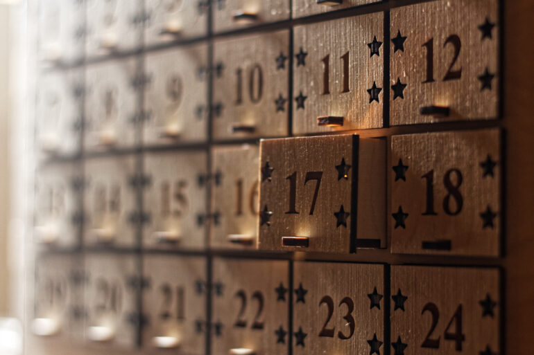 A close-up of a wooden advent calendar with mini box drawers and the calendar dates engraved on the box faces.