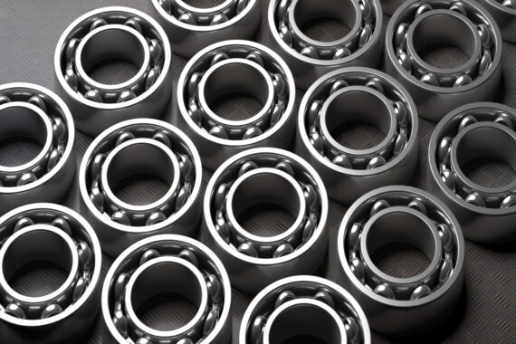 Four rows of bearings lie flat on a dark gray background. The bearings are shiny and made of metal.