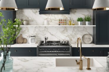 A modern kitchen with a granite island counter and a backsplash, a stainless-steel oven, and grey cabinets.
